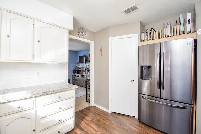 kitchen with white cabinetry, light stone countertops, tasteful backsplash, dark hardwood / wood-style flooring, and stainless steel fridge