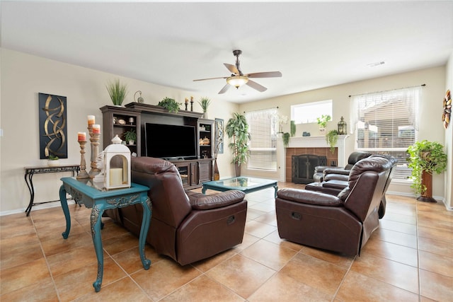 living room with light tile patterned floors, visible vents, baseboards, a tiled fireplace, and ceiling fan