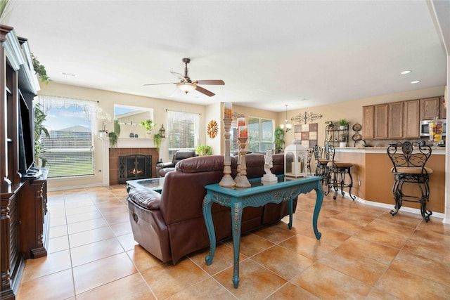 living room with ceiling fan, plenty of natural light, a fireplace, and light tile patterned flooring