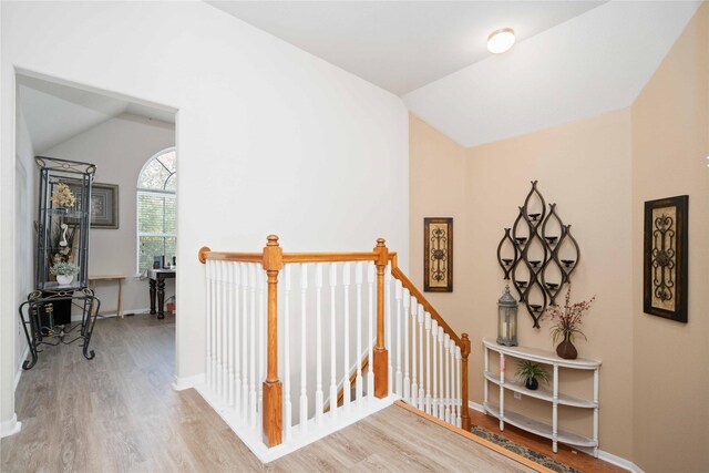 stairway with wood-type flooring and lofted ceiling