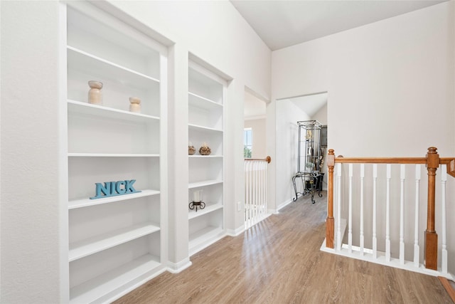 hallway with light hardwood / wood-style flooring and vaulted ceiling