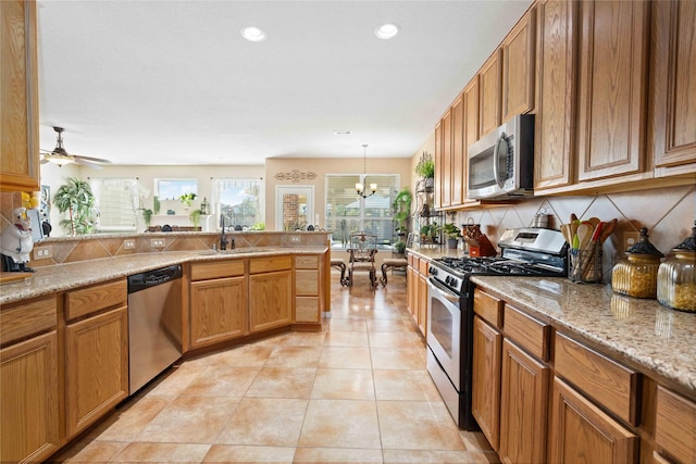 kitchen featuring ceiling fan with notable chandelier, pendant lighting, stainless steel appliances, sink, and light tile patterned floors