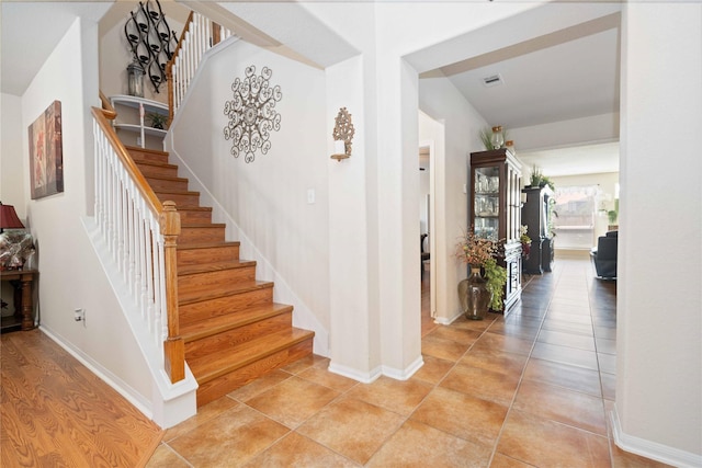 stairway featuring tile patterned flooring, visible vents, and baseboards