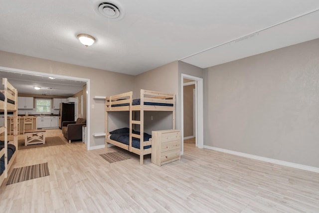 bedroom featuring black fridge and light hardwood / wood-style floors