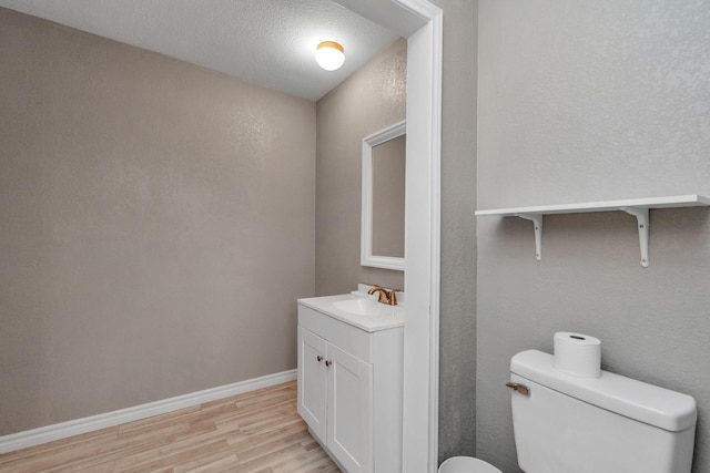 bathroom with hardwood / wood-style flooring, vanity, toilet, and a textured ceiling