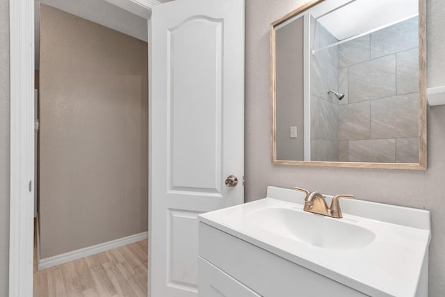 bathroom with tiled shower, vanity, and hardwood / wood-style flooring