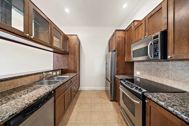 kitchen with backsplash, dark stone counters, sink, light tile patterned floors, and stainless steel appliances