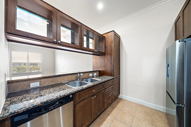 kitchen with sink, crown molding, dark stone countertops, light tile patterned floors, and stainless steel appliances