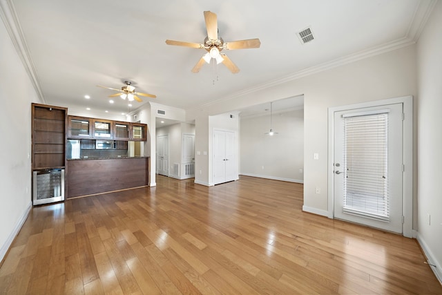 unfurnished living room featuring ceiling fan, light wood-type flooring, and ornamental molding