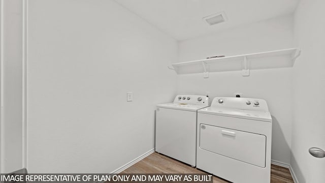 laundry area with washer and dryer and light hardwood / wood-style floors