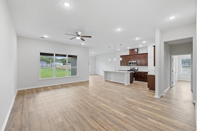 unfurnished living room featuring ceiling fan, sink, and light wood-type flooring