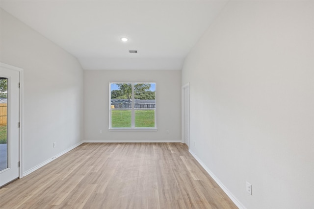 spare room with vaulted ceiling and light hardwood / wood-style flooring