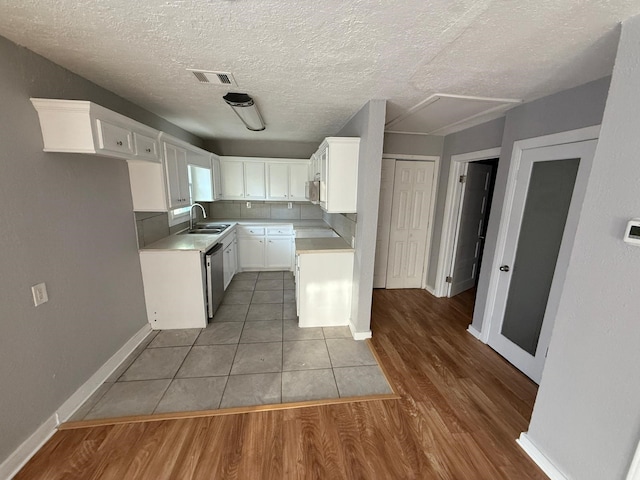 kitchen featuring sink, stainless steel appliances, dark hardwood / wood-style flooring, a textured ceiling, and white cabinets