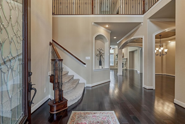 foyer entrance with an inviting chandelier, dark hardwood / wood-style floors, and ornamental molding