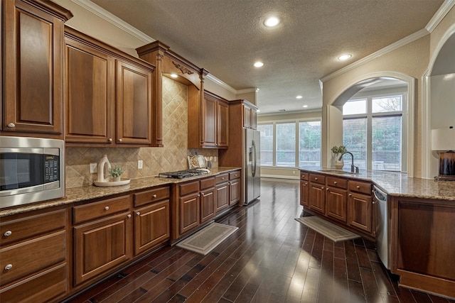 kitchen featuring light stone countertops, sink, backsplash, appliances with stainless steel finishes, and ornamental molding