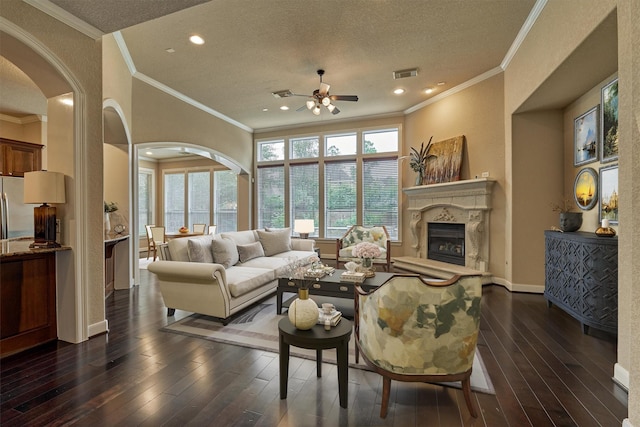 living room featuring ornamental molding, a textured ceiling, ceiling fan, and dark wood-type flooring