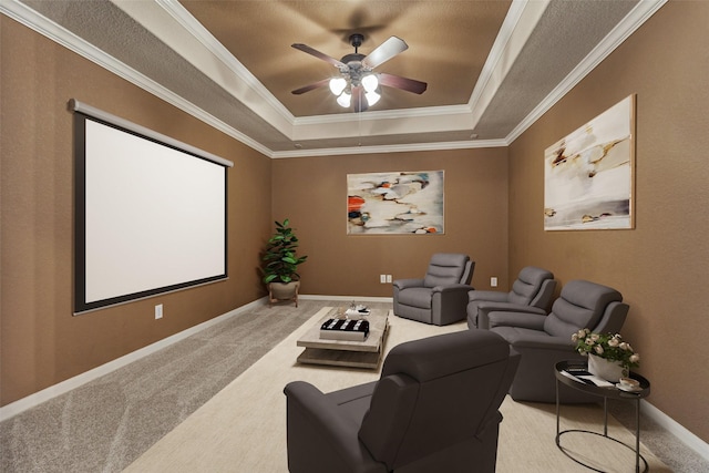 carpeted home theater with a tray ceiling, crown molding, and ceiling fan