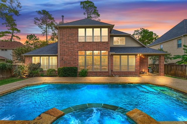 pool at dusk featuring an in ground hot tub