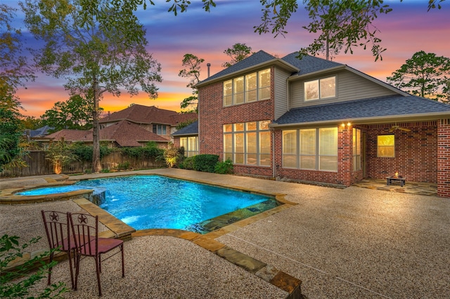 pool at dusk featuring an in ground hot tub and a patio area