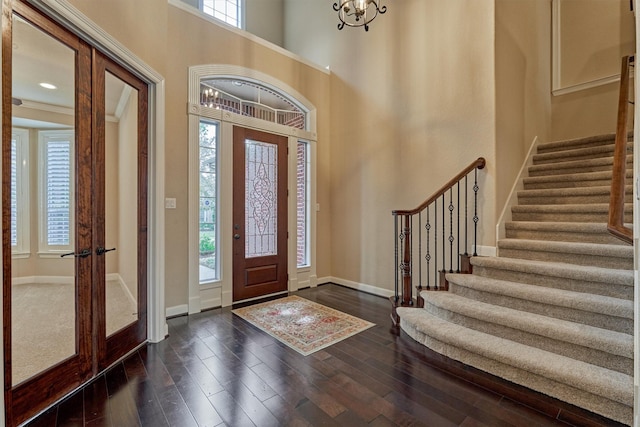 entrance foyer with an inviting chandelier, dark wood-type flooring, a high ceiling, and french doors