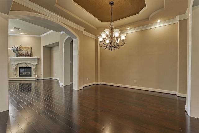 unfurnished living room featuring dark wood-type flooring, a high end fireplace, an inviting chandelier, a raised ceiling, and ornamental molding