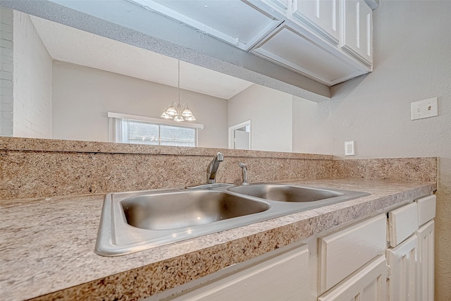 kitchen with a chandelier, decorative light fixtures, white cabinets, and sink