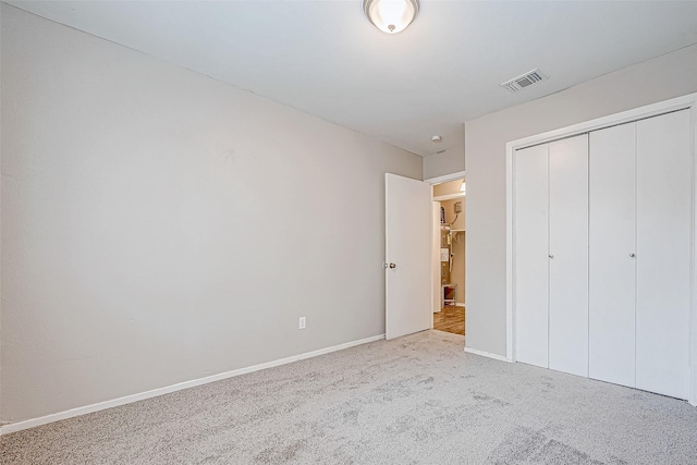 unfurnished bedroom with light carpet and a closet