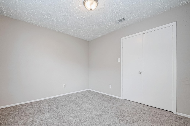 unfurnished bedroom featuring a closet, carpet, and a textured ceiling