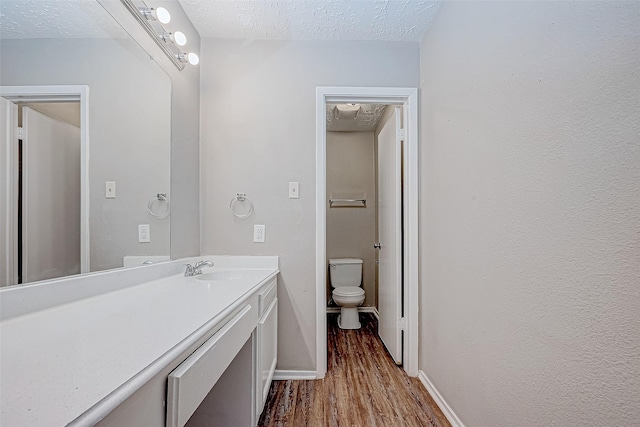 bathroom featuring vanity, toilet, wood-type flooring, and a textured ceiling