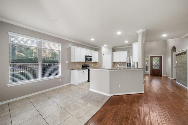 kitchen with white cabinetry, crown molding, appliances with stainless steel finishes, and light wood-type flooring