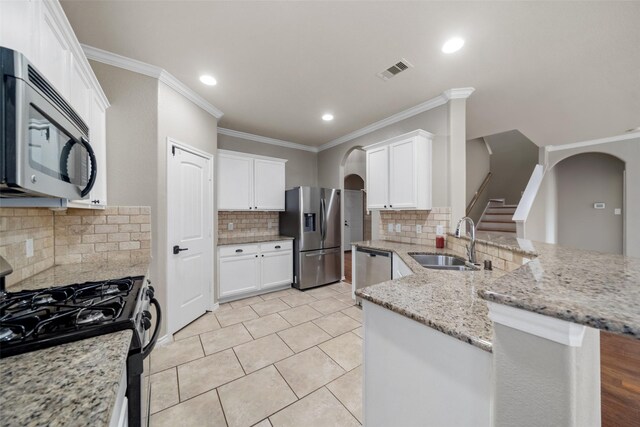 kitchen featuring white cabinets, sink, appliances with stainless steel finishes, tasteful backsplash, and kitchen peninsula