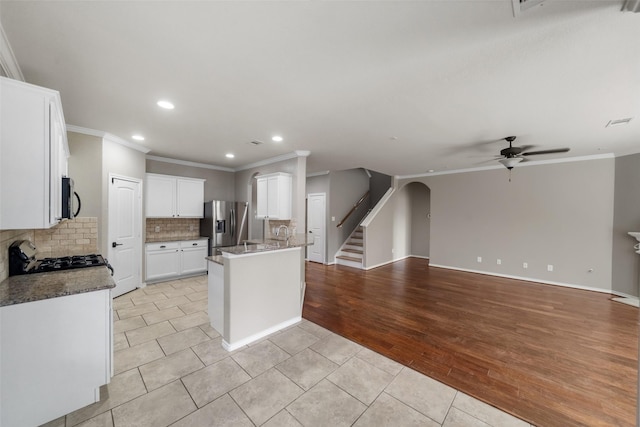 kitchen with ceiling fan, tasteful backsplash, light wood-type flooring, white cabinets, and appliances with stainless steel finishes