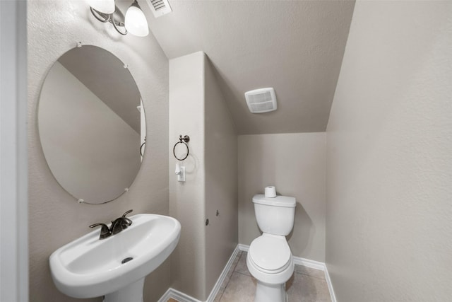 bathroom with tile patterned floors, sink, lofted ceiling, and toilet