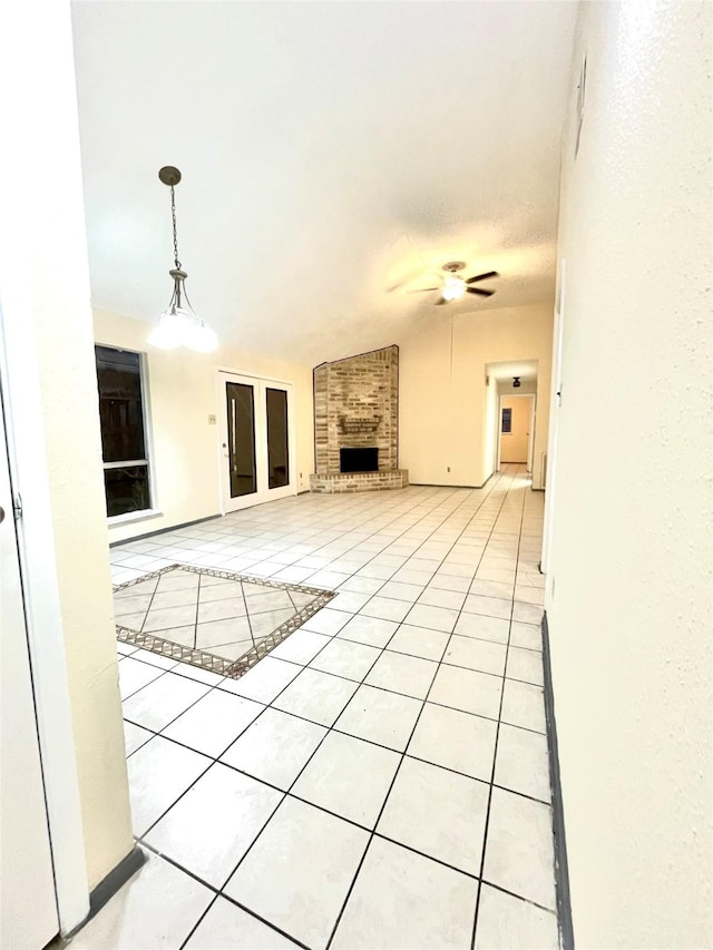 unfurnished living room with ceiling fan, a textured ceiling, lofted ceiling, a fireplace, and light tile patterned flooring