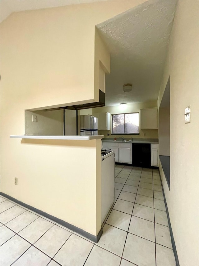 kitchen featuring kitchen peninsula, refrigerator, sink, white cabinets, and light tile patterned flooring