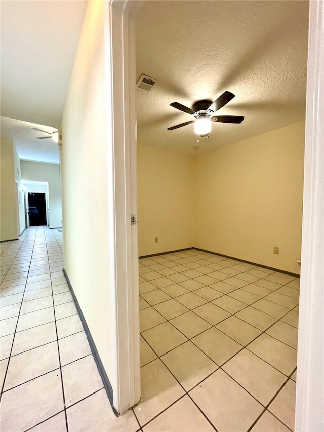 corridor featuring light tile patterned floors and a textured ceiling