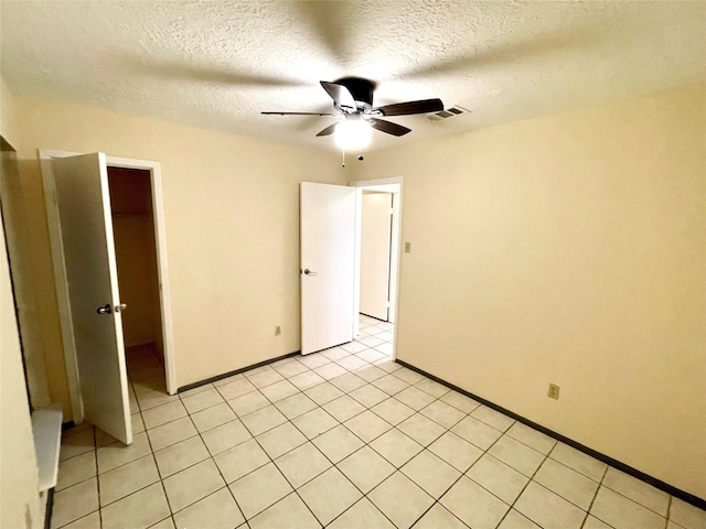 unfurnished room with ceiling fan, light tile patterned floors, and a textured ceiling