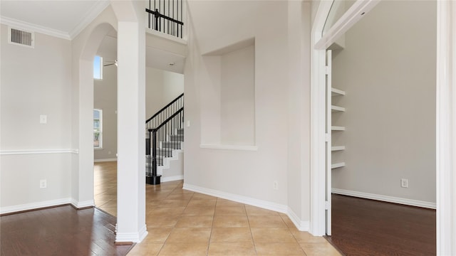 entryway with ceiling fan, ornamental molding, a towering ceiling, and light hardwood / wood-style flooring