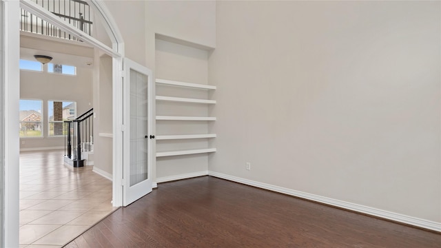 unfurnished room with french doors, wood-type flooring, and a high ceiling