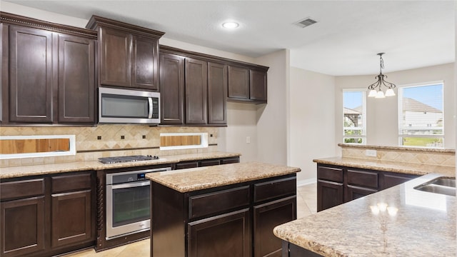 kitchen with a center island, a chandelier, decorative light fixtures, light tile patterned floors, and appliances with stainless steel finishes