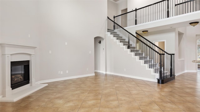 unfurnished living room with light tile patterned flooring and a towering ceiling