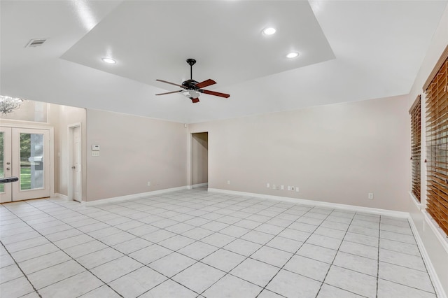 tiled spare room featuring a raised ceiling, ceiling fan, and french doors