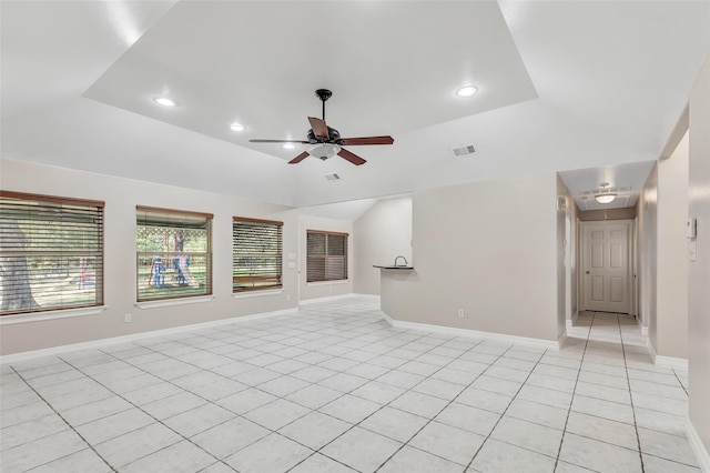 unfurnished living room featuring a raised ceiling, ceiling fan, and light tile patterned flooring