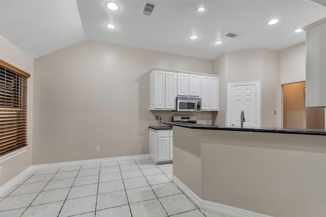 kitchen with lofted ceiling, range, kitchen peninsula, light tile patterned flooring, and white cabinetry