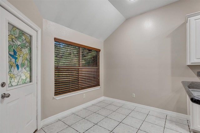 unfurnished dining area with light tile patterned floors and vaulted ceiling