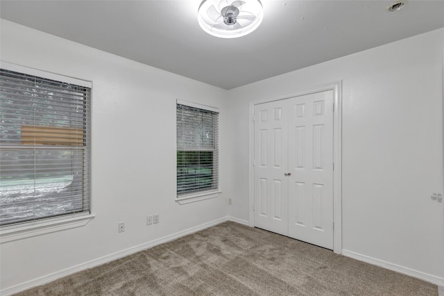 unfurnished bedroom with light colored carpet and a closet