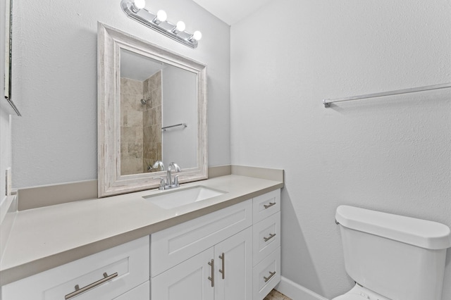 bathroom featuring toilet, a tile shower, and vanity