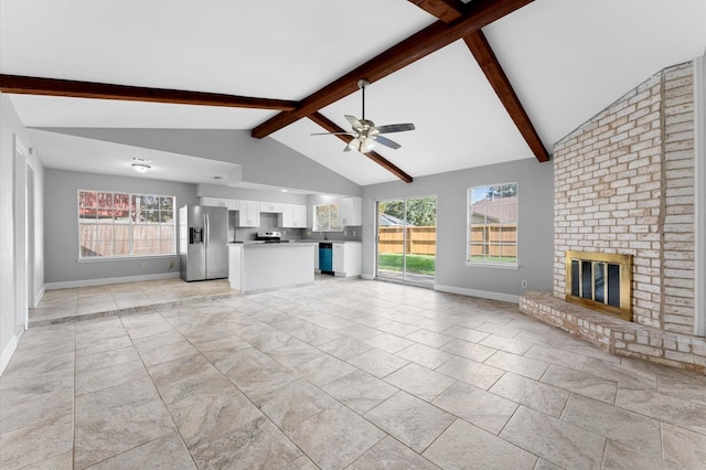 unfurnished living room featuring lofted ceiling with beams, a fireplace, baseboards, and a healthy amount of sunlight