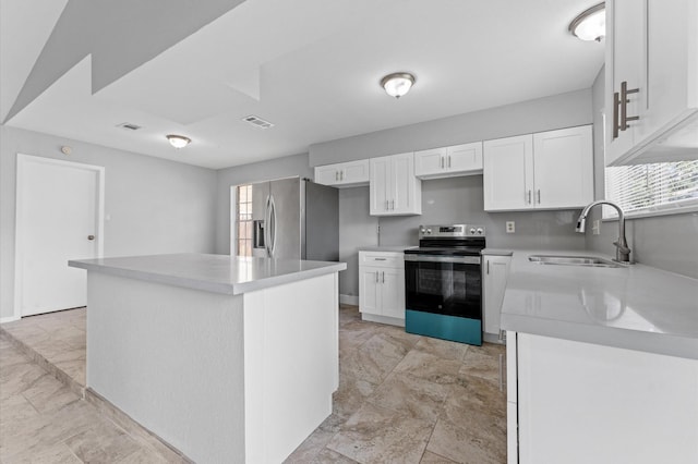 kitchen with light countertops, appliances with stainless steel finishes, a sink, and white cabinetry