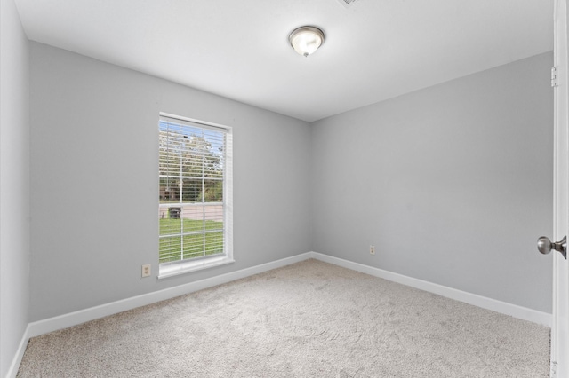 spare room featuring carpet floors and baseboards